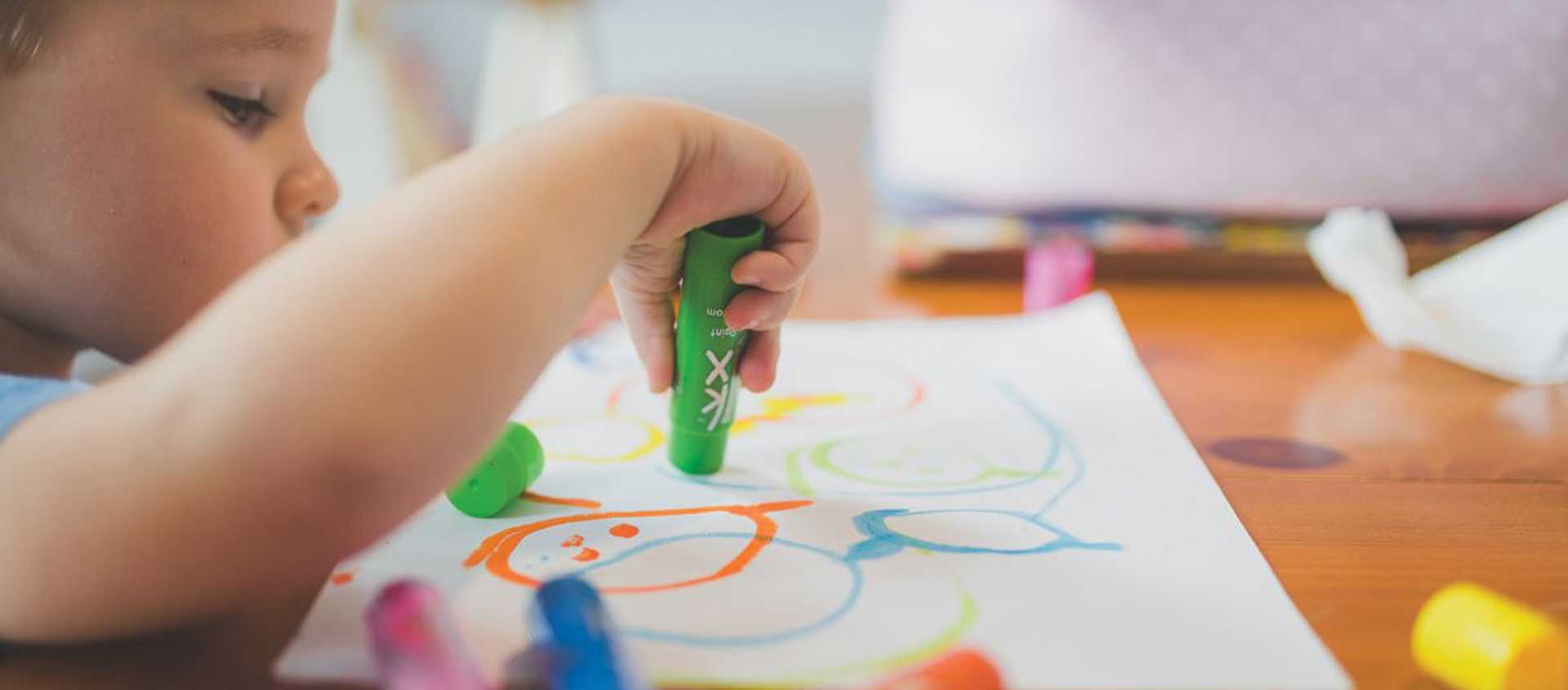 A preschooler uses a marker to draw.
