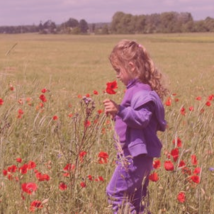 A girl with blond hair picks flowers in a field.
