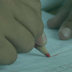A child's hands draw a line on graph paper.