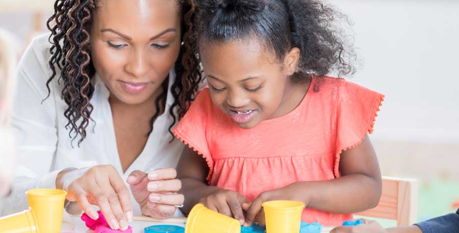 A Black American woman and child play with play dough together.