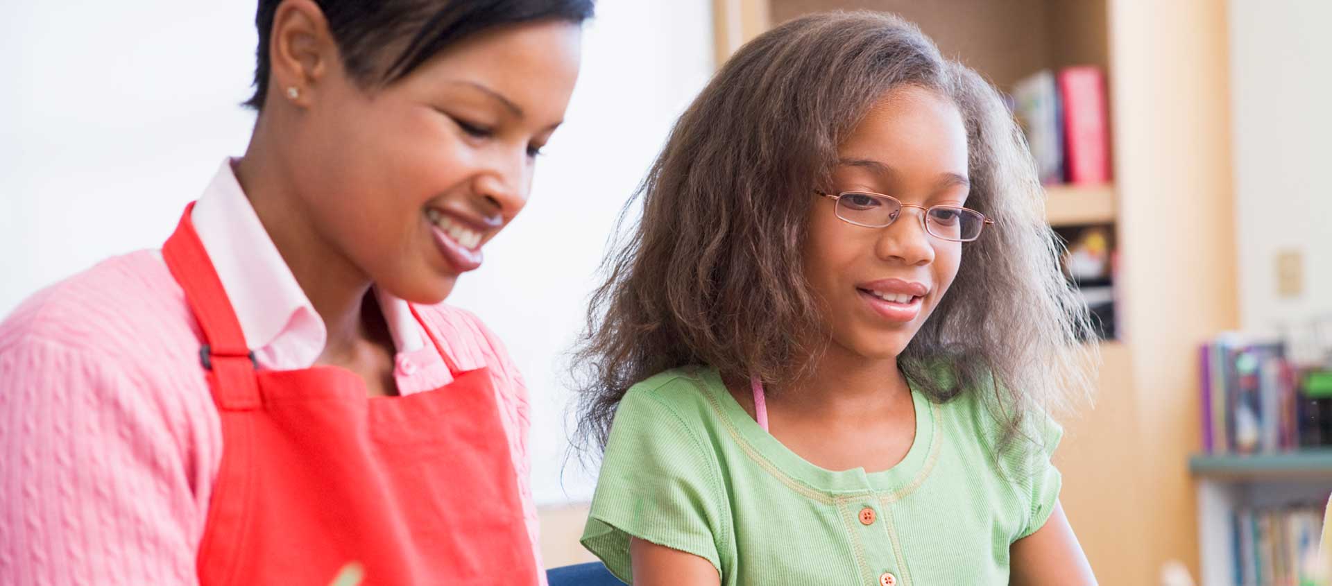 A Black American girl and her teacher working together.