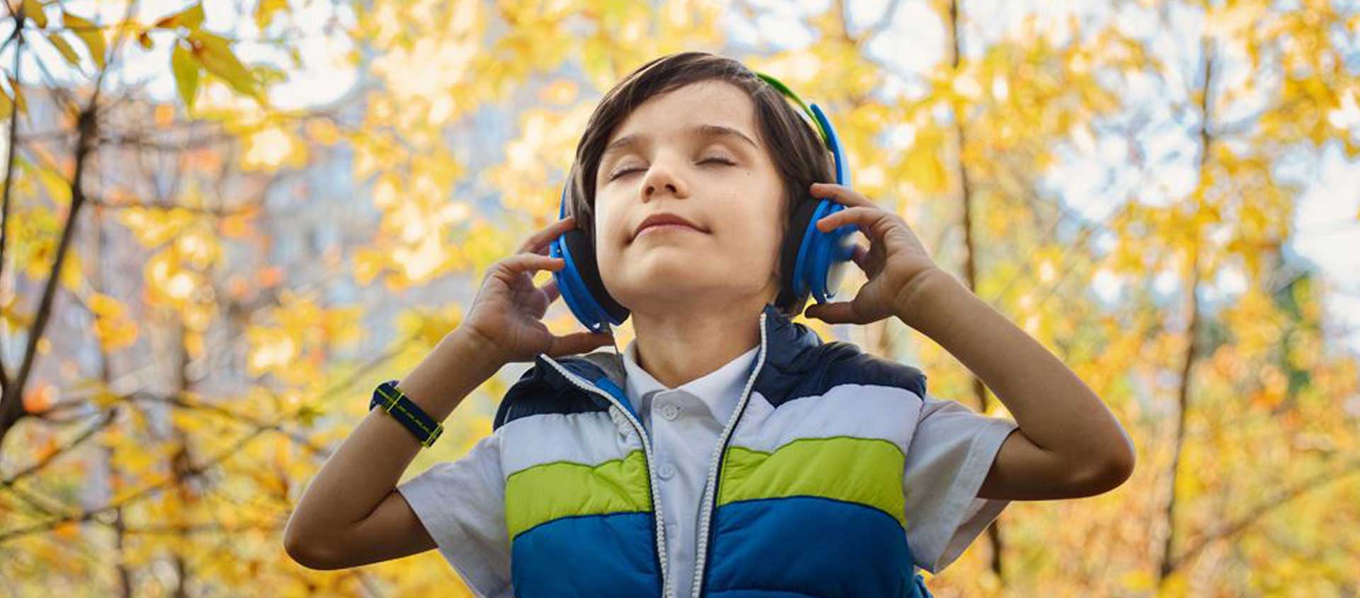 A peaceful-looking boy wearing headphones outdoors.
