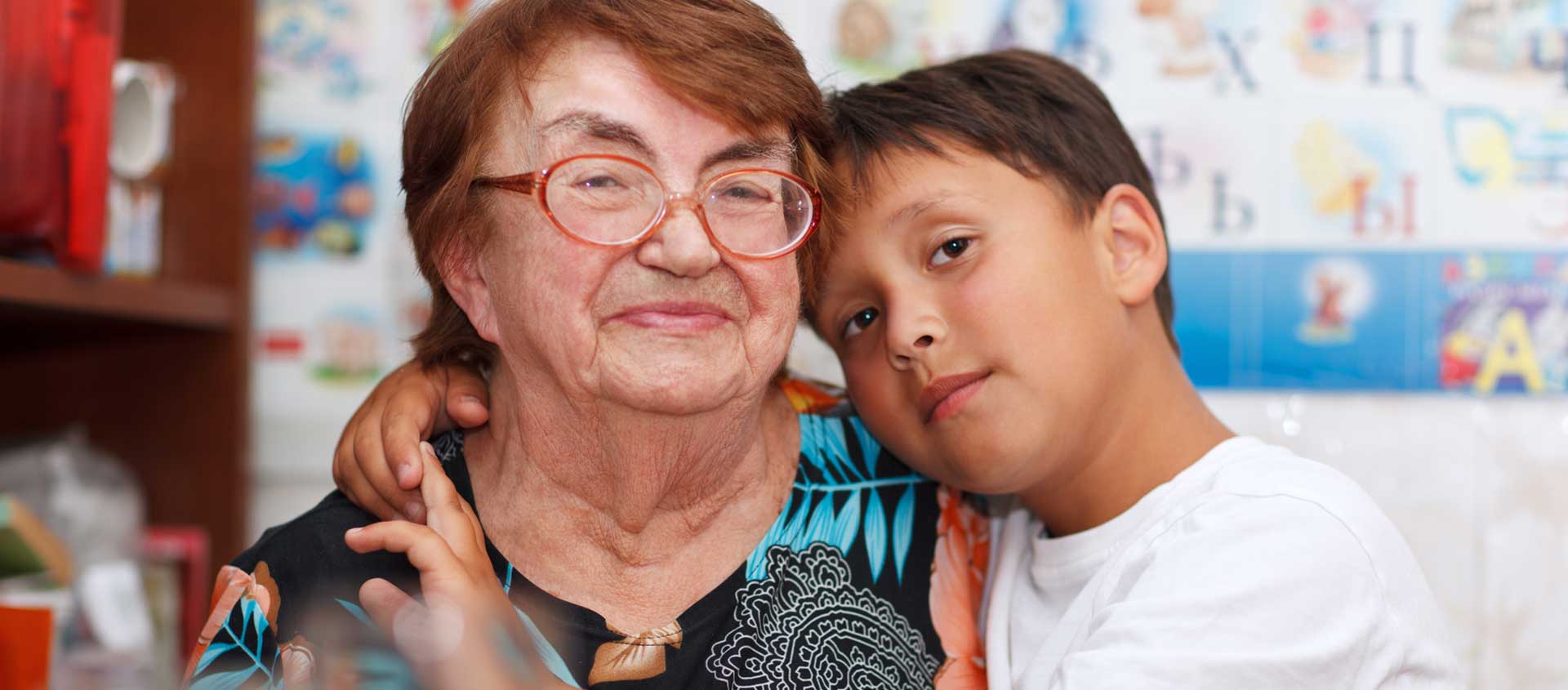 A pre-teen boy and his grandmother face the camera in a half embrace.